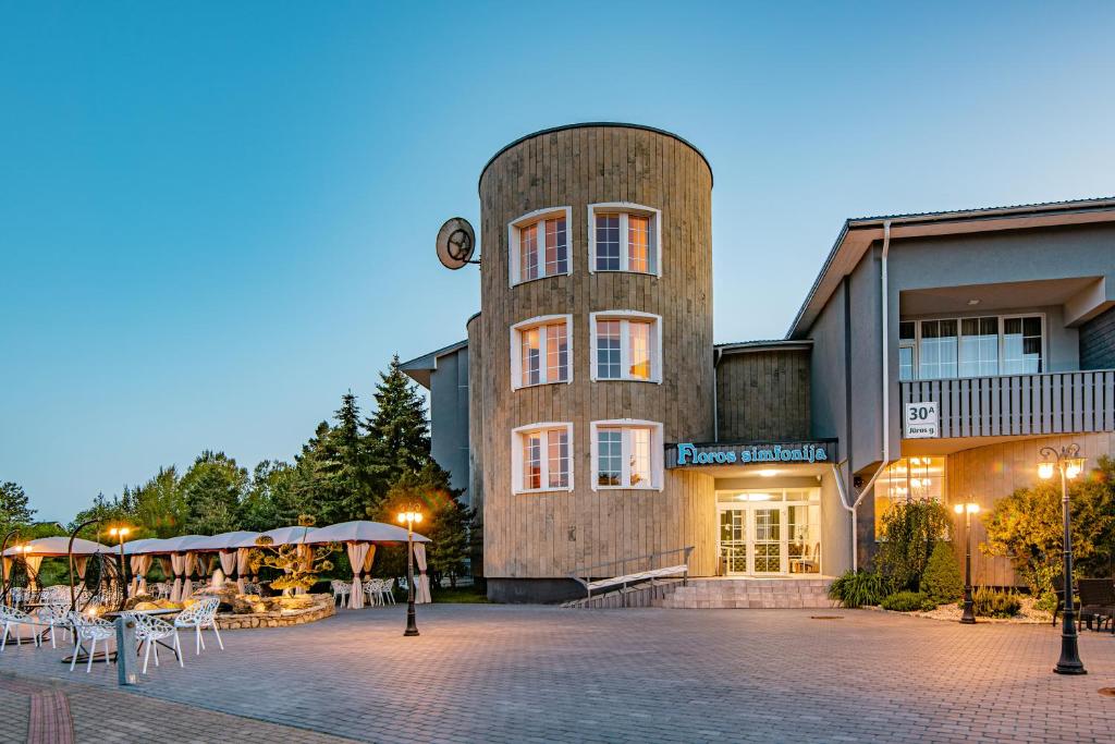a building with a tower with tables and chairs at Floros simfonija Jūros in Šventoji
