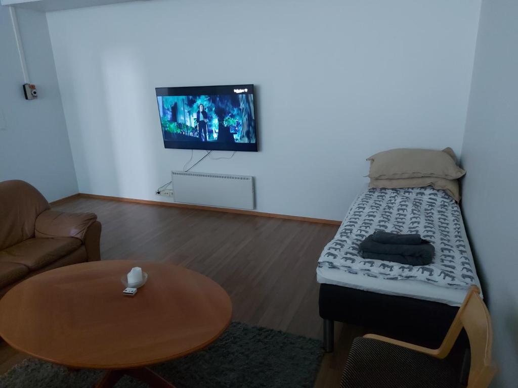 Apartment Junki في Alavieska: غرفة معيشة مع سرير مع طاولة وتلفزيون