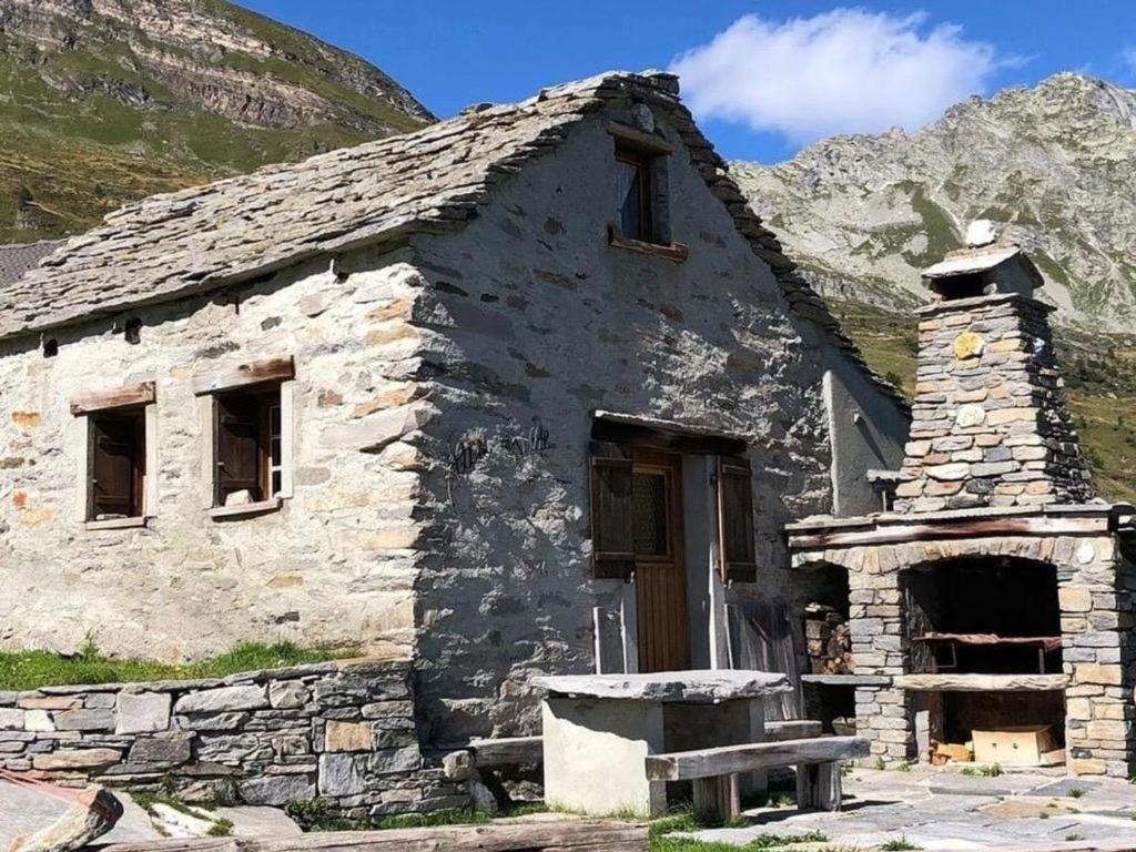 an old stone building with a bench in front of it at Rustico "Casi Hütte" in Bosco Gurin