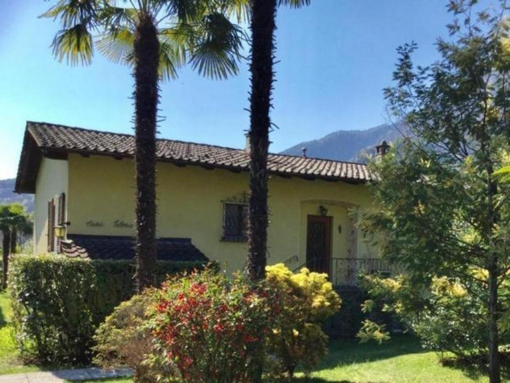 una casa amarilla con palmeras en el patio en "CASA ELENA -Tegna" die Ruheoase in grossem mediterranem Garten en Tegna