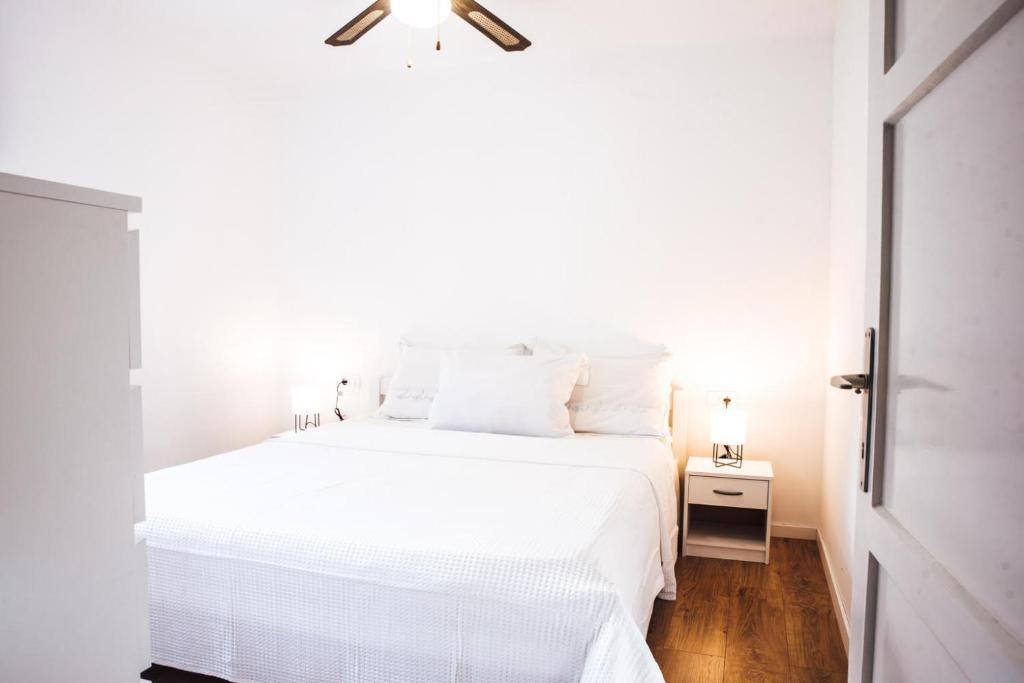 a white bed with white sheets and a ceiling fan at Old Town Watch&C in Korčula