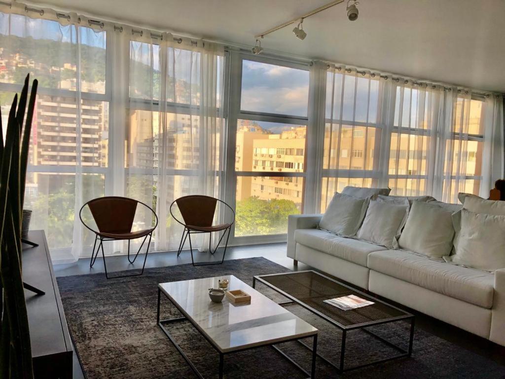 sala de estar con sofá blanco y ventanas grandes en Ipanema com Todo Conforto, en Río de Janeiro