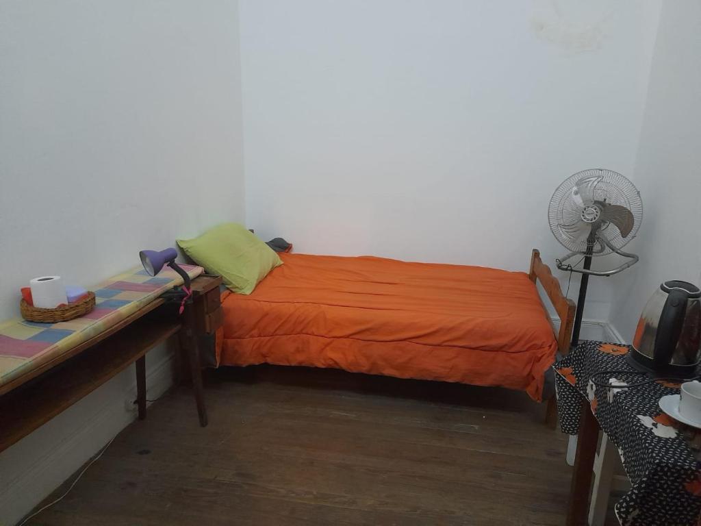 1 dormitorio con 1 cama con manta naranja y ventilador en Corazón de Recoleta en Buenos Aires