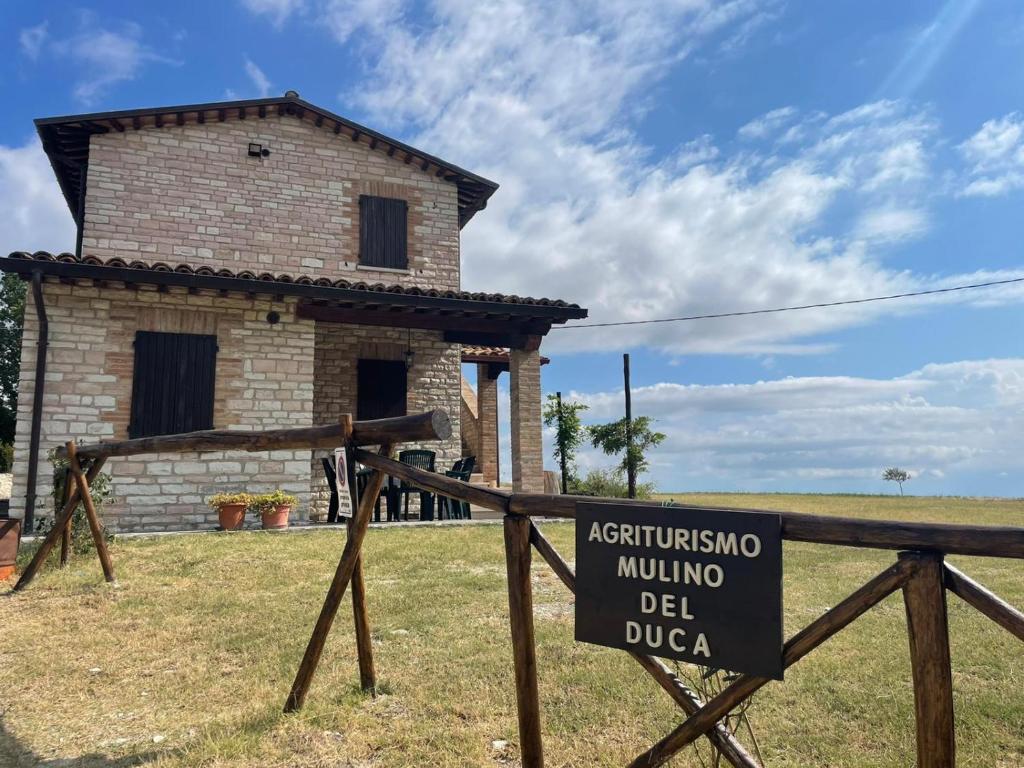 um sinal em frente a um edifício de tijolos com uma casa em Agriturismo Mulino del Duca em Urbino