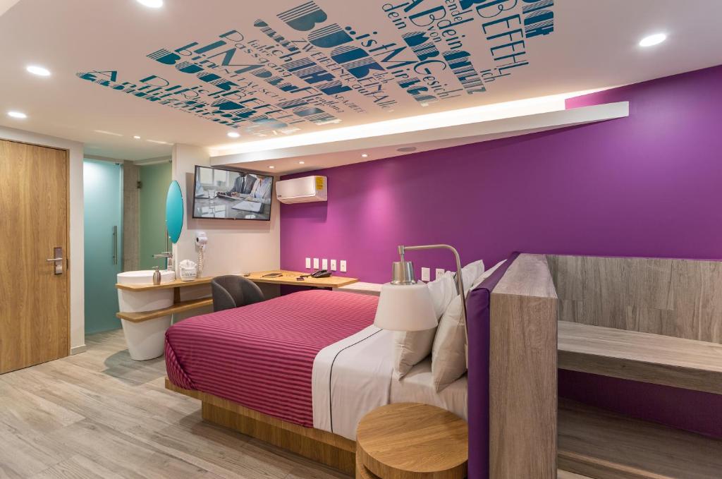Habitación de hotel con cama y pared púrpura en Hotel Bonn en Ciudad de México