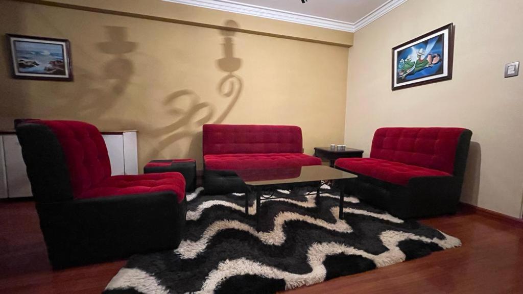 a living room with two red chairs and a rug at Departamento Lincoln Cochabamba in Cochabamba