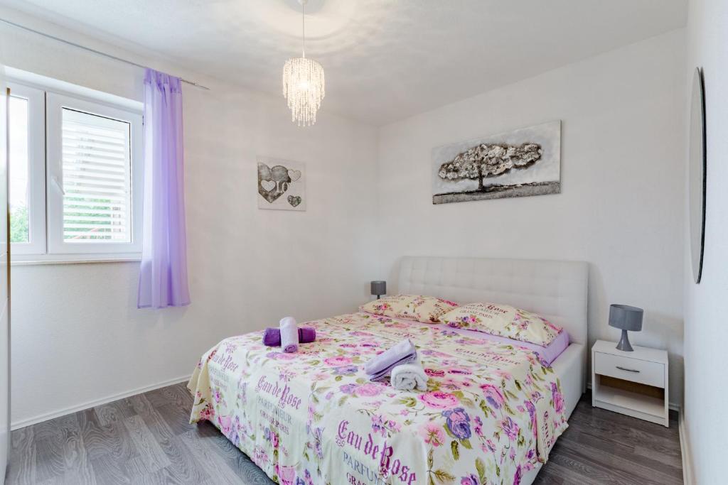 a white bedroom with a bed with purple curtains at Apartment Anamaris in Solin