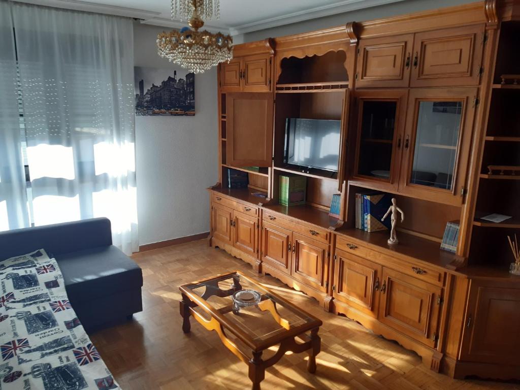 ein Wohnzimmer mit einem großen Unterhaltungszentrum aus Holz in der Unterkunft Apartamento Brañavalera in Pola de Lena