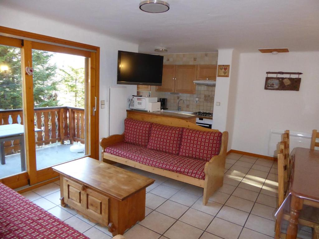 un salon avec un canapé rouge et une cuisine dans l'établissement Chalet spacieux avec terrasse, proche commerces et télécabine, garage et parking inclus - FR-1-464-37, à Champagny-en-Vanoise
