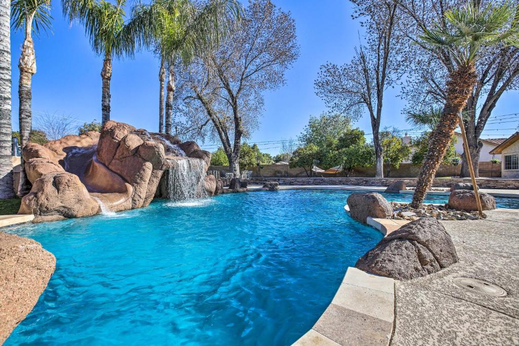 a pool in a resort with a waterfall and palm trees at Spacious Glendale Home with Outdoor Kitchen! in Glendale