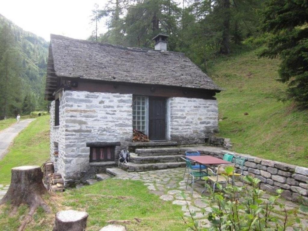 a small stone house with a table in front of it at Rustico Bersacola in Bosco Gurin
