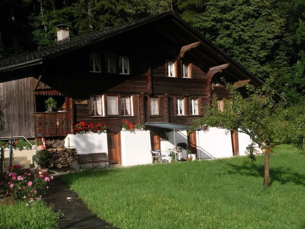 uma grande casa de madeira com um quintal com relvado em 4-Bett- Ferienwohnung Brachli em Innertkirchen