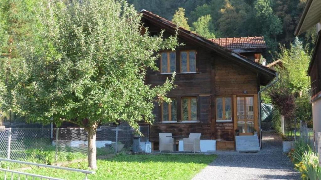 uma casa de madeira com uma árvore em frente em Ursula und Daniel 6-Bettwohnung Meiringen em Meiringen