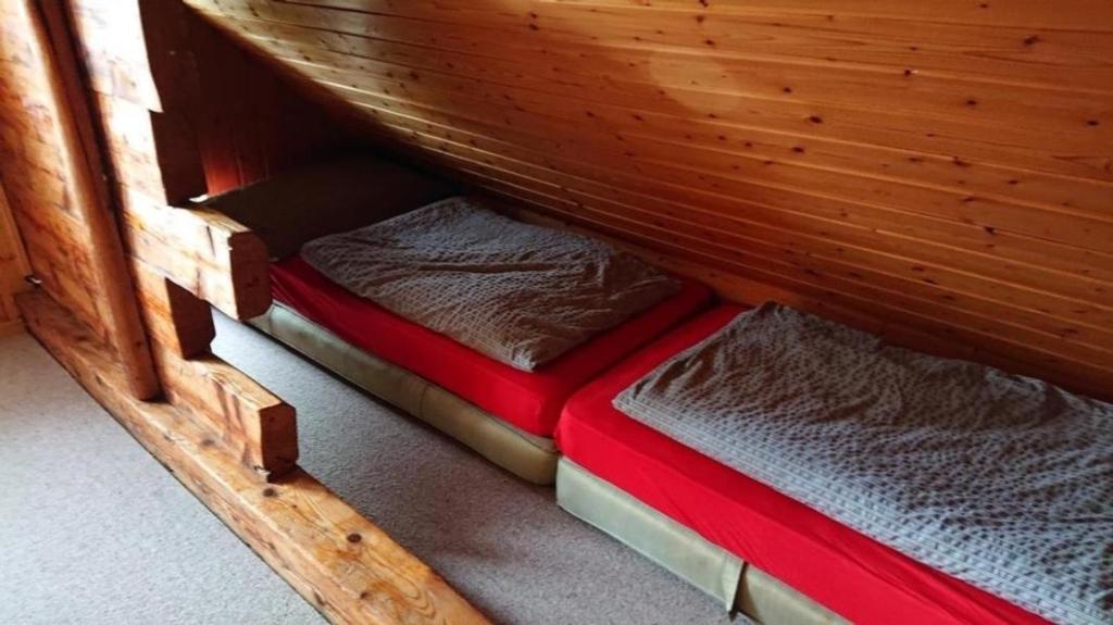 a small bed in a wooden cabin with a red mattress at Ferien in der Vogelherd in Wolfhalden 