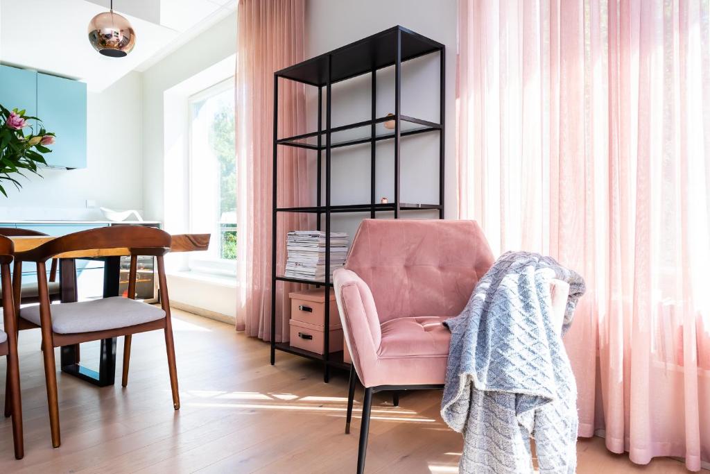 a living room with a pink chair and a desk at Fabulous Location Apartments Deluxe in Tallinn