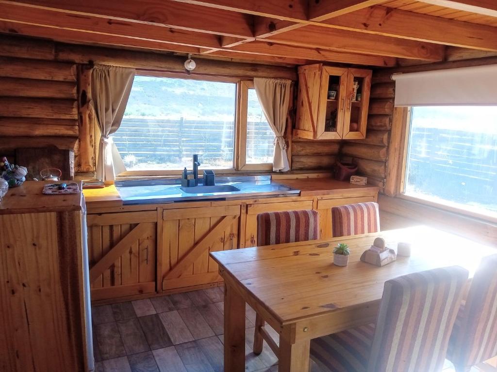 una cocina con mesa y fregadero en una cabaña en Cabañas Don Luis en Junín de los Andes