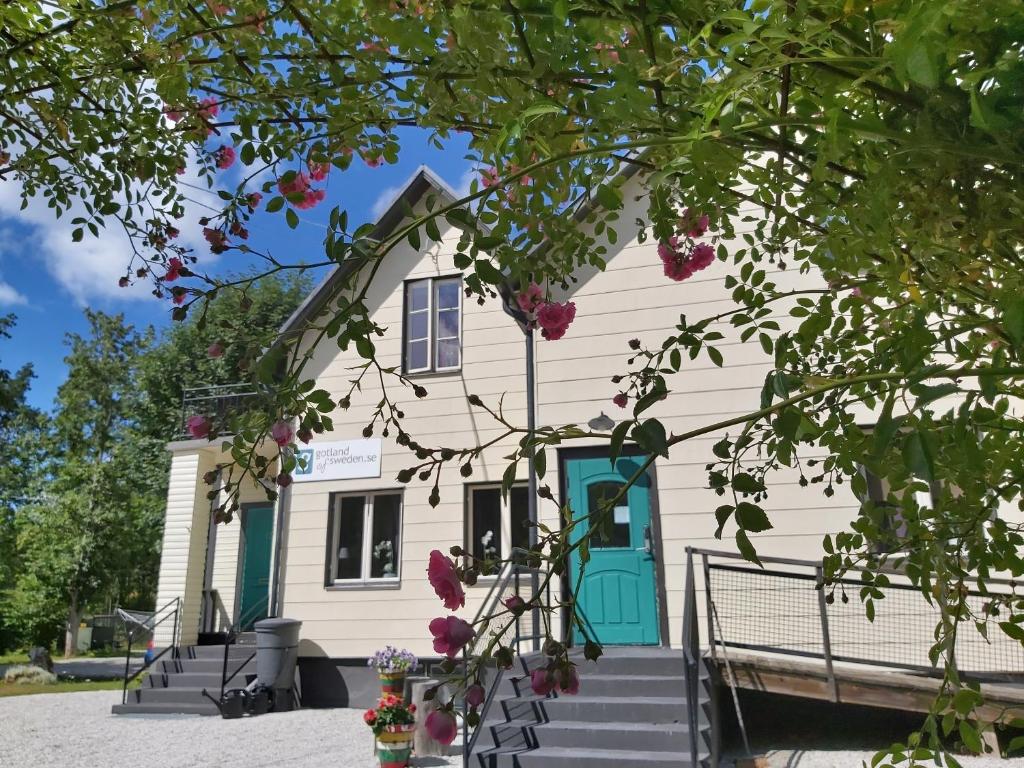Tingstäde的住宿－Gotland of Sweden - bed & breakfast，白色的房子,有蓝色的门和一些花