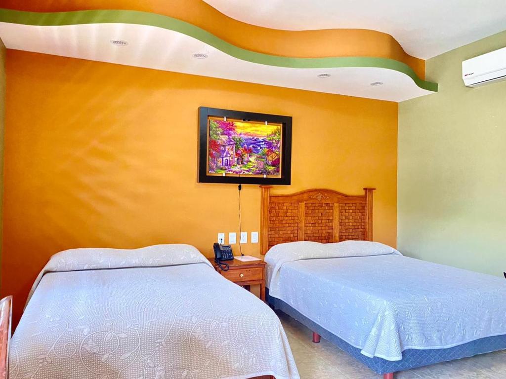 ein Schlafzimmer mit 2 Betten und einem Wandgemälde in der Unterkunft HOTEL RESTAURANTE TEQUILA in Jalpan de Serra