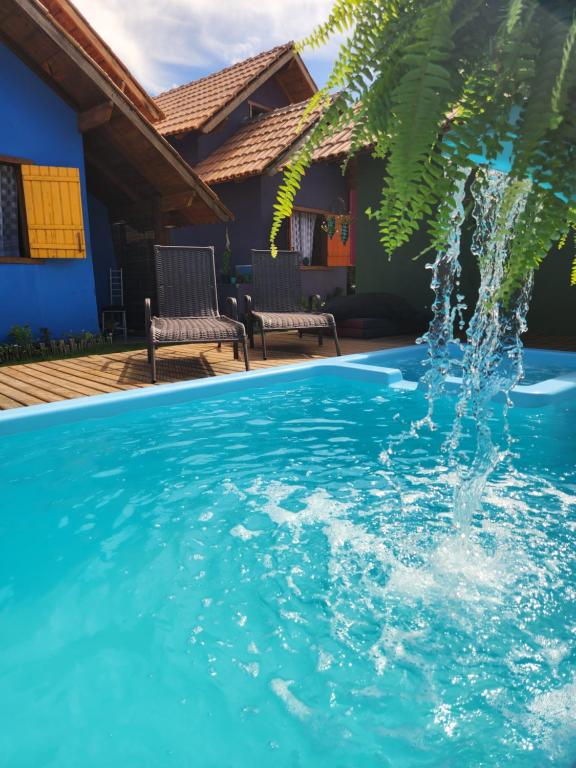 a swimming pool with a fountain in front of a house at Chalés Cabocla da Lua in Caraíva
