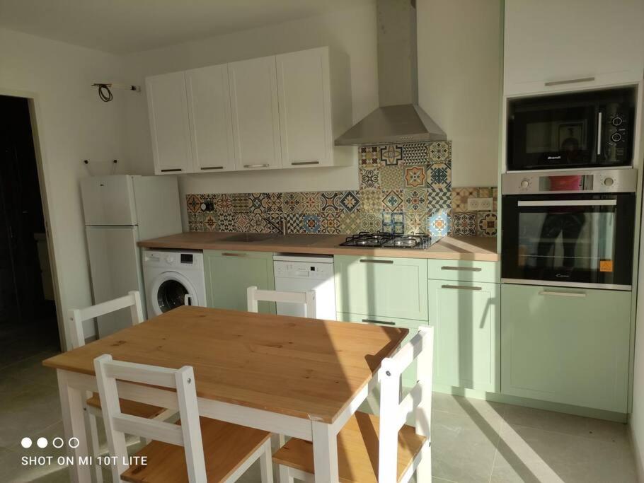 cocina con armarios blancos y mesa de madera en L'Affacatoghju - Grand studio au village (2p), en Tavera