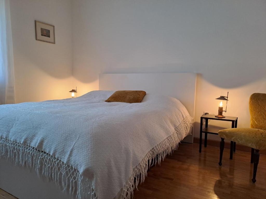 um quarto com uma grande cama branca e uma cadeira em Dal Nonno, casa vacanze em Trieste