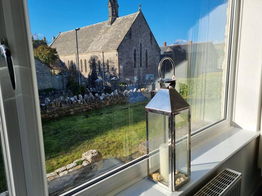 a window with a lantern in front of a church at Church View - 2 bed Cosy Cottage in Swanage in Swanage