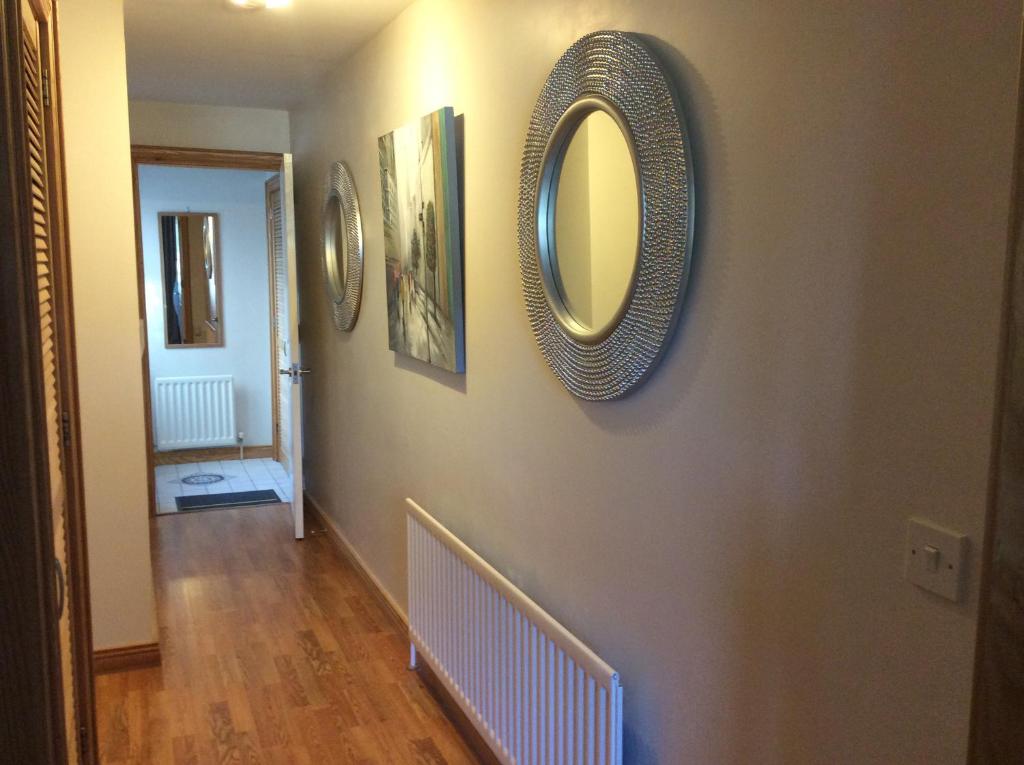 a hallway with a mirror and pictures on the wall at Apiary Mews in Newcastle