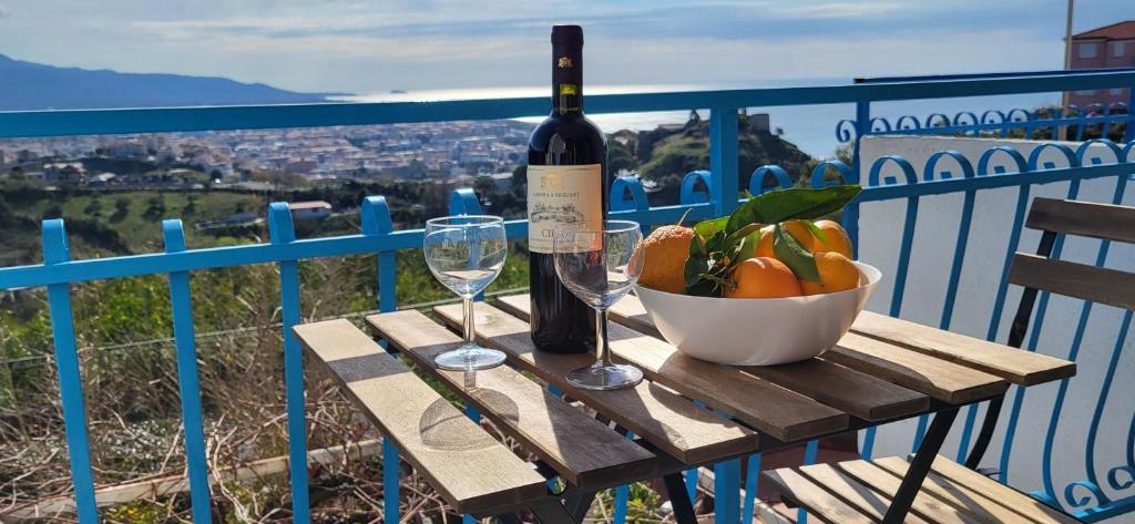 una botella de vino y un bol de fruta en una mesa en Sull'Onda, en Scalea