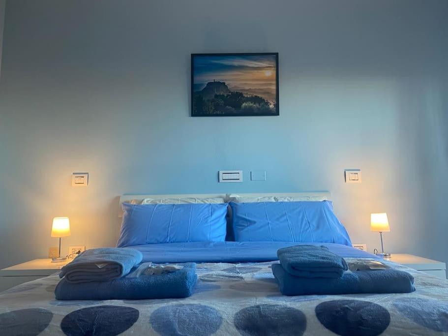 ein blaues Schlafzimmer mit einem Bett mit zwei blauen Kissen in der Unterkunft Civita Home in Bagnoregio
