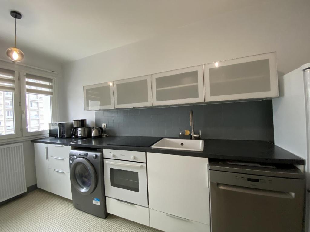 a kitchen with white cabinets and a washing machine at Superbe appartement proche de Paris in Colombes