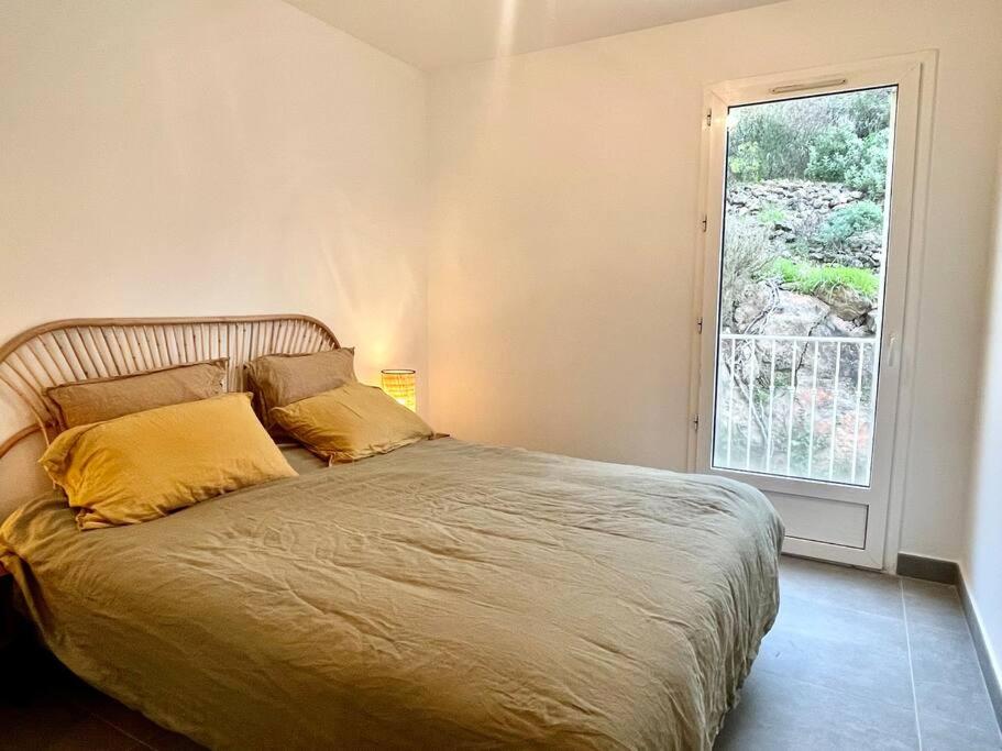 ein Bett mit gelben Kissen in einem Schlafzimmer mit Fenster in der Unterkunft Vue panoramique - résidence calme - St Raphaël in Saint-Raphaël