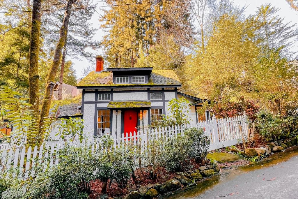 een klein huis met een wit hek en een rode deur bij Cascade Cottage in Mill Valley