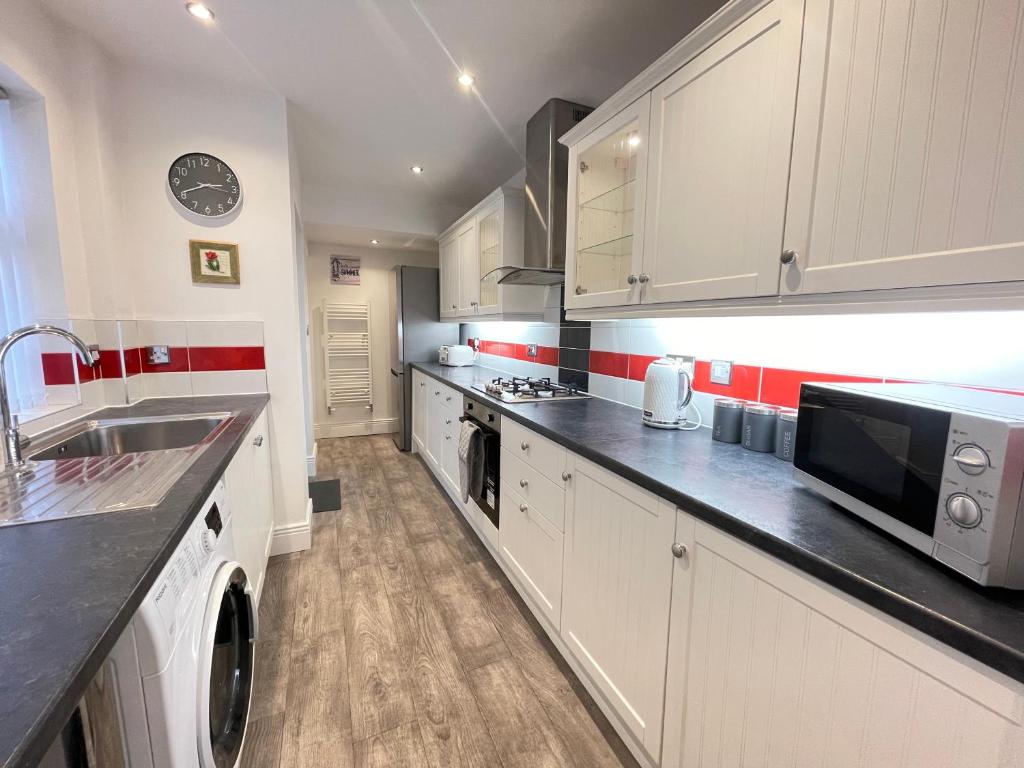 a kitchen with white cabinets and black counter tops at Marine Apartment Whitley Bay Seaside Location Free Onsite Parking in Whitley Bay