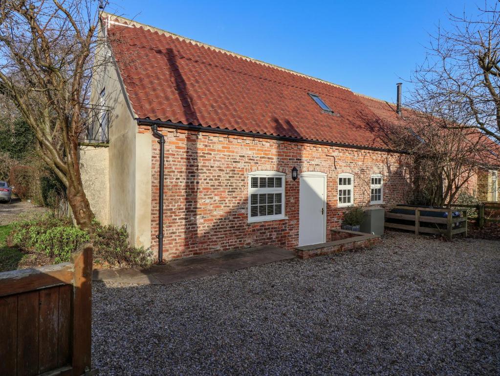 a brick house with a white door and a red roof at The Dower House Cottage in Carthorpe