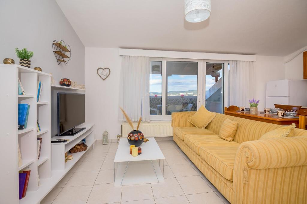 a living room with a yellow couch and a tv at City Melody Apartment with Private Parking in Alexandroupoli
