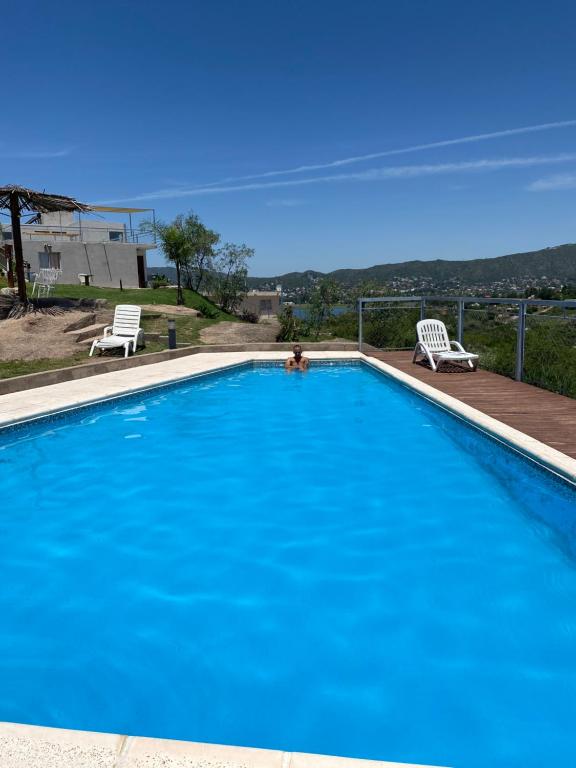 een groot blauw zwembad met twee stoelen en een persoon erin bij Vista del Lago in Villa Carlos Paz