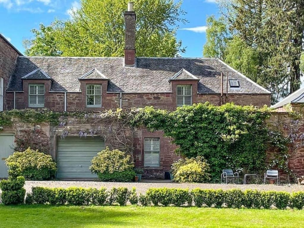 une maison en briques avec un garage dans une cour dans l'établissement Reidochie Stables luxury haven overlooking garden, à Blairgowrie