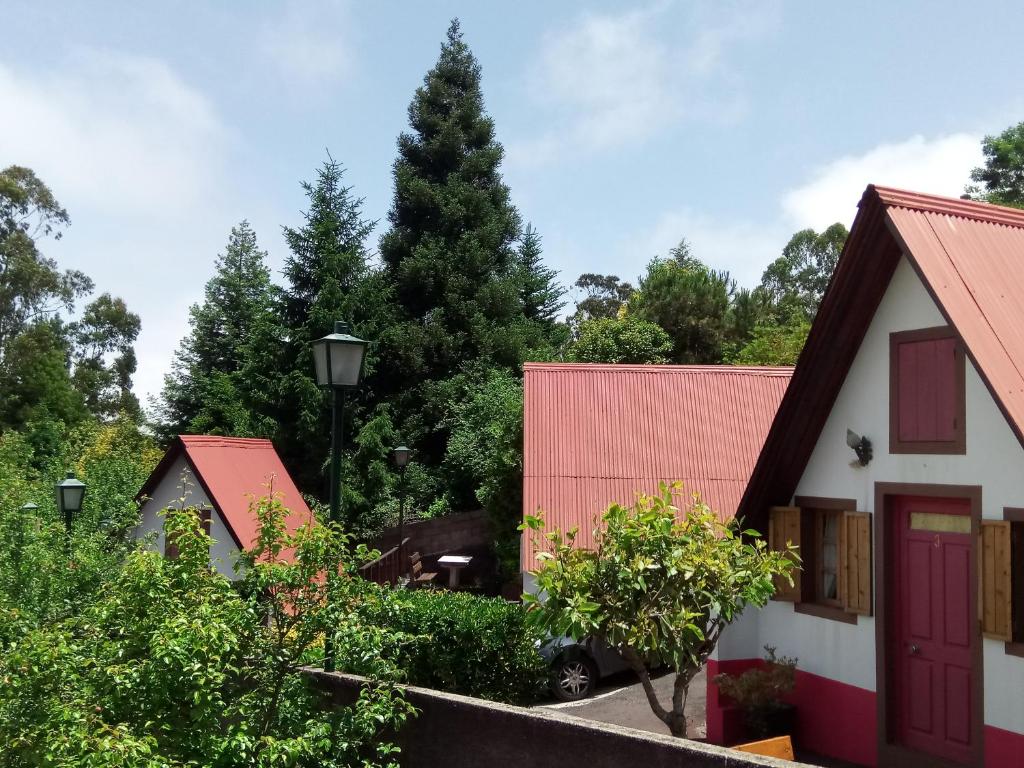 eine Gruppe von Häusern mit einem Baum im Hintergrund in der Unterkunft Abrigo da Serra- Nature Trails in Santana