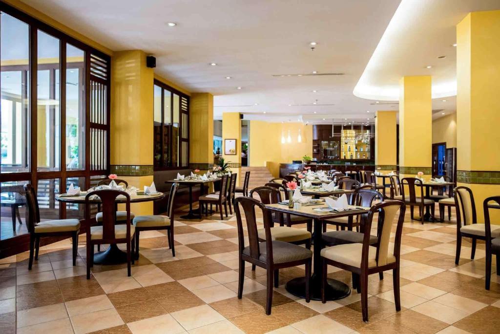 uma sala de jantar com mesas e cadeiras num restaurante em Mercure Chiang Mai em Chiang Mai