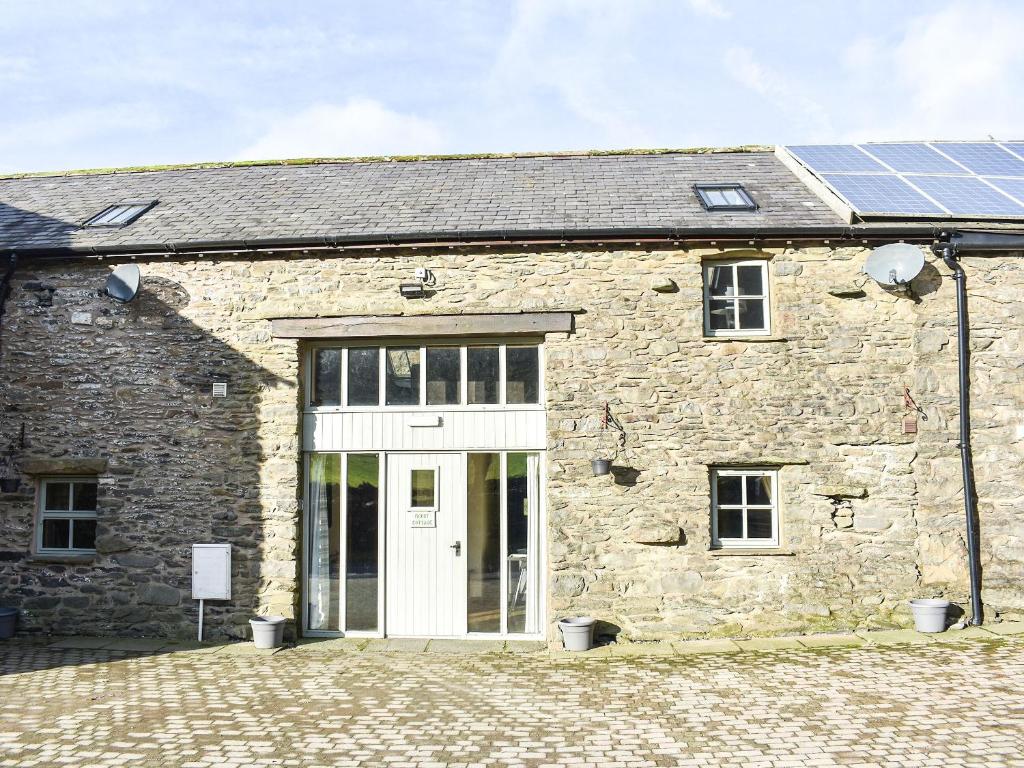 a stone building with a white door and solar panels at Mount Cottage-uk42230 in Low Borrowbridge