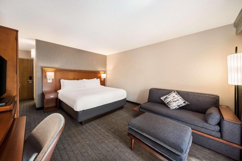 um quarto de hotel com uma cama e um sofá em Sonesta Select San Jose Airport em San José
