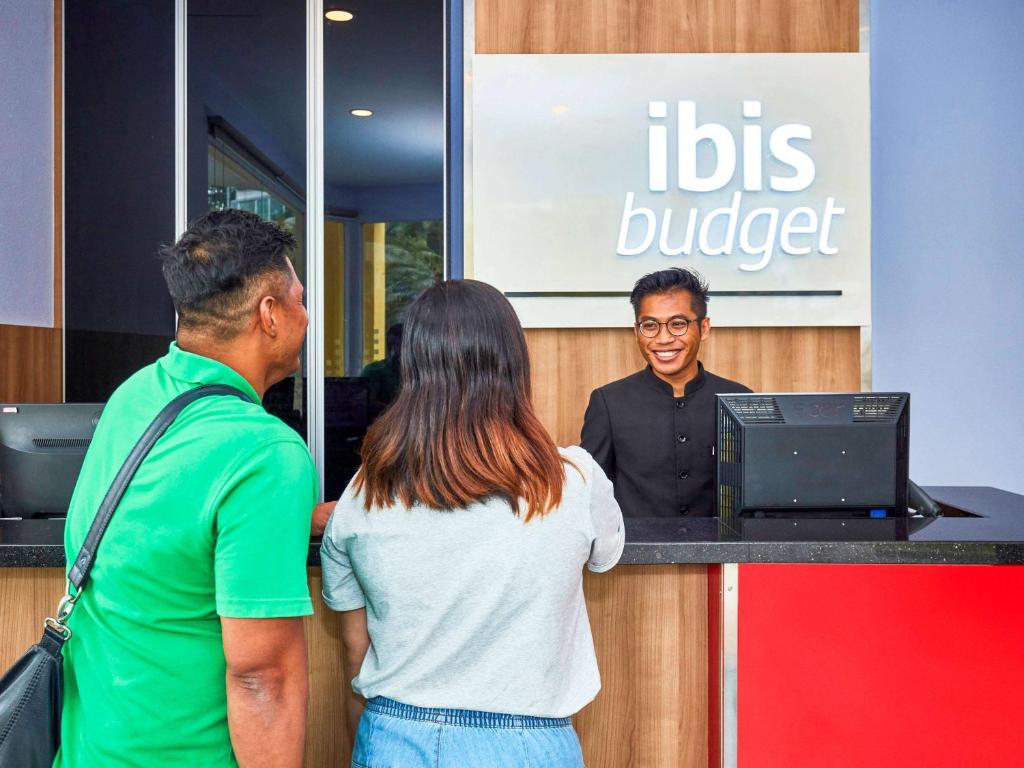 ibis budget Singapore West Coast في سنغافورة: رجل وامرأه يقفان عند ارسال الباص