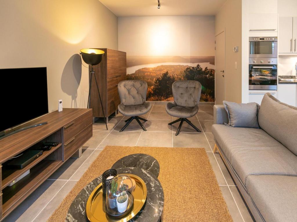 Maasmechelen Duplex Retreat في ماسميشلين: غرفة معيشة مع أريكة وكرسيين
