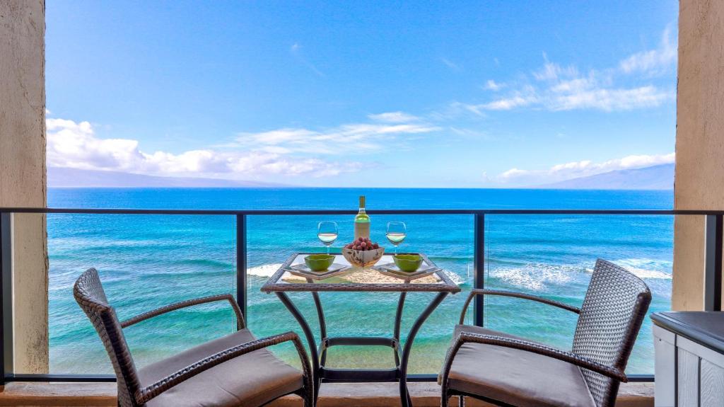 een tafel en stoelen op een balkon met uitzicht op de oceaan bij Maui Westside Presents: Mahana 1003 in Lahaina