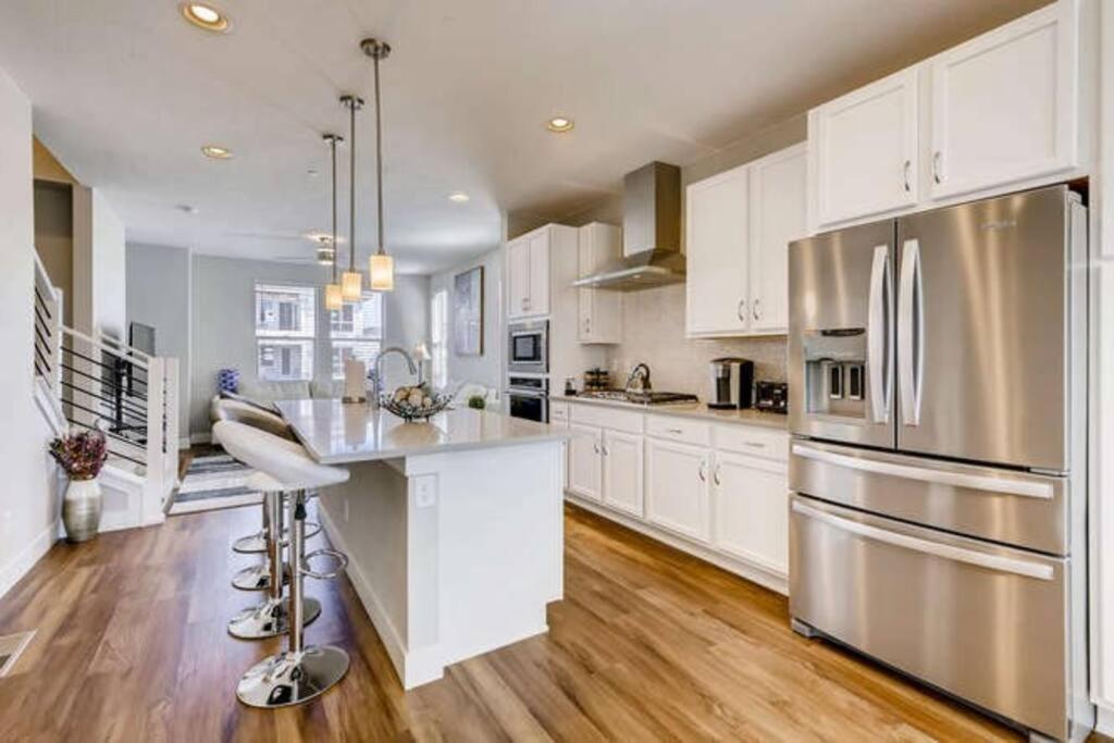 a kitchen with white cabinets and a stainless steel refrigerator at Luxury Oasis! in Denver