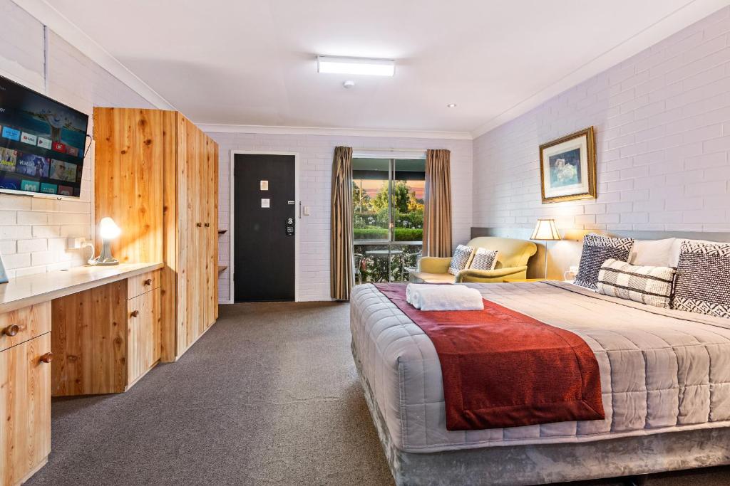 a bedroom with a large bed and a living room at Burringa Garden Motel in Wagga Wagga