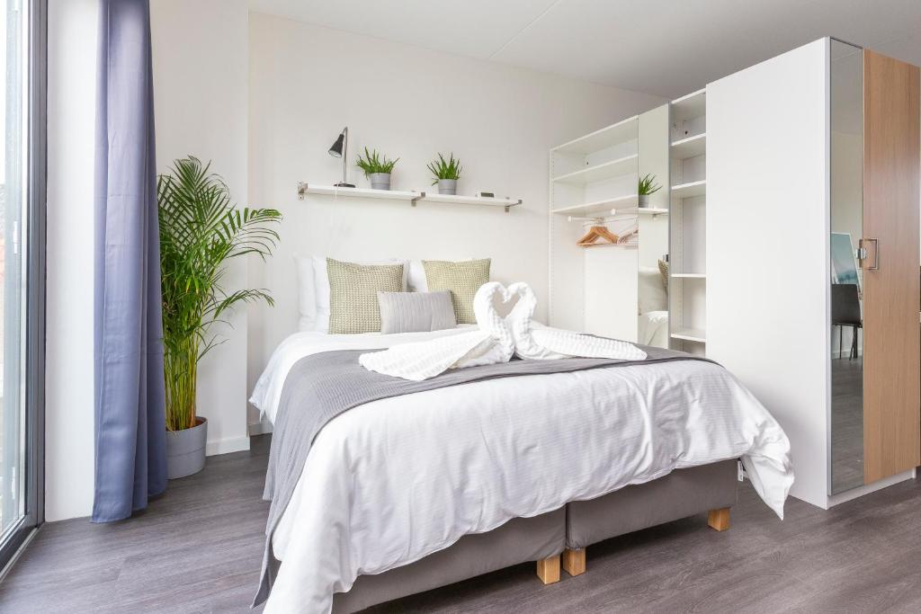 a white bedroom with a large bed and plants at Luxurious loft w-view walk city Center Delft New XL Apartment in Delft
