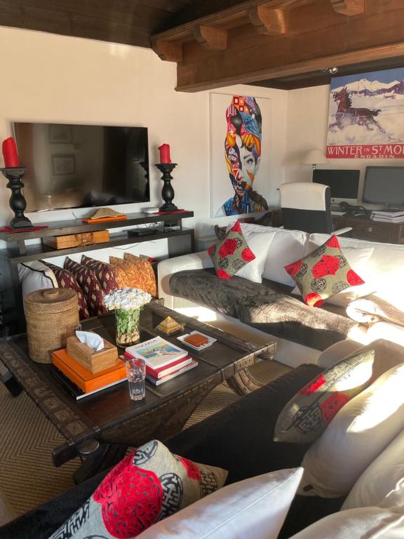 uma sala de estar com sofás e uma mesa com almofadas em Chalet OG Harfe em Davos