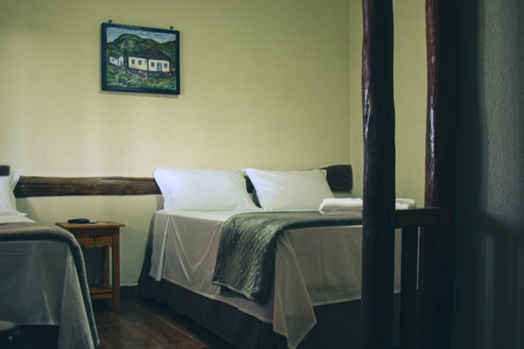 a bedroom with a bed with white pillows at Pousada Chalés do Rancho Canastra in Vargem Bonita