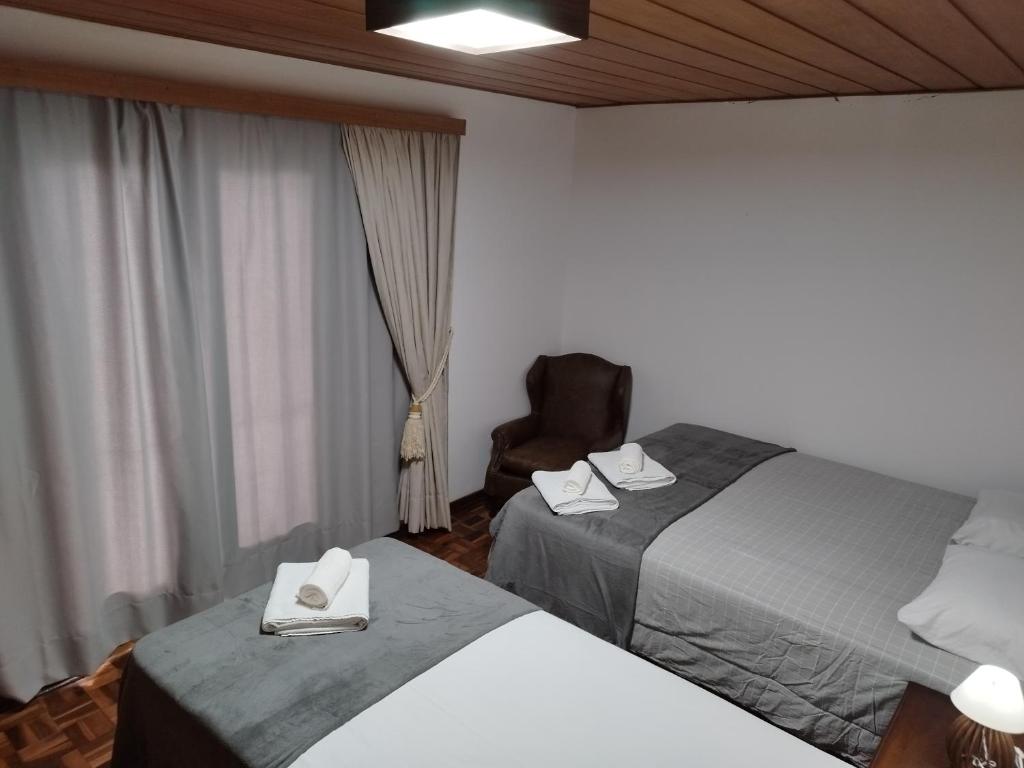 Pokój hotelowy z 2 łóżkami i krzesłem w obiekcie Château Capivari - Campos do Jordão w mieście Campos do Jordão